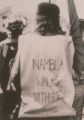 Harry Hay marching at the 1986 Los Angeles gay pride parade wearing a cloth sign reading "NAMBLA Walks With Me", before the pride organizers and cops forced him to remove his message before joining the parade.